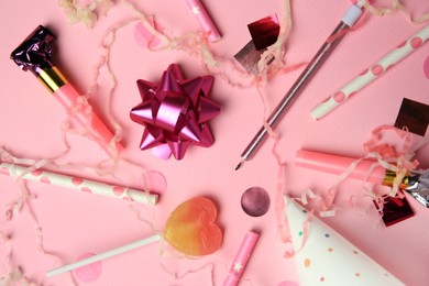 Party blowers, lollipop and festive decor on pink background, flat lay