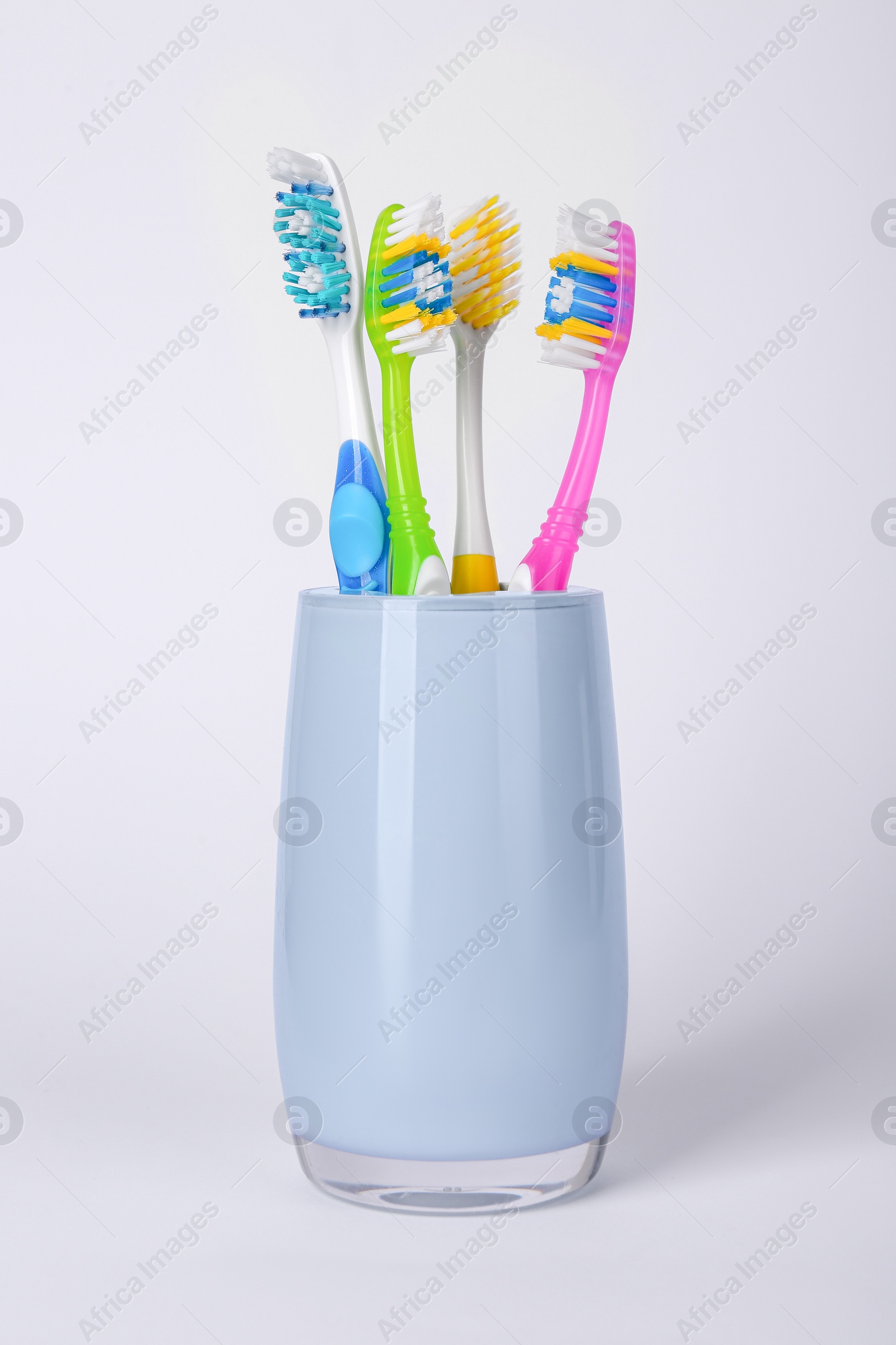 Photo of Different toothbrushes in holder on light grey background