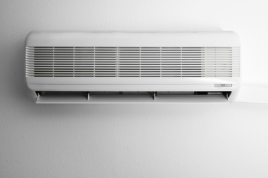 Photo of Modern air conditioner on white wall indoors