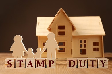 Image of Stamp duty. Family and house wooden figures on table