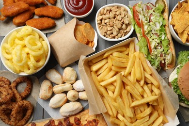 French fries, chips other fast food on gray wooden table, flat lay