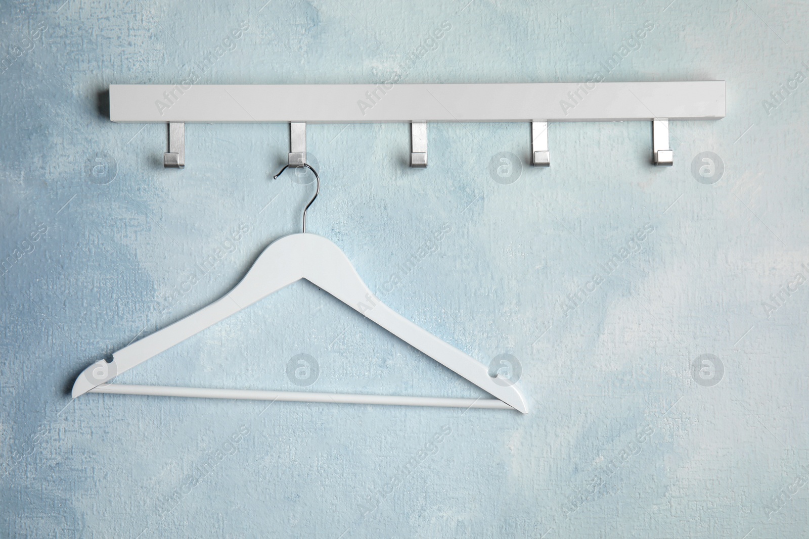 Photo of Rack with empty clothes hanger on color wall, space for text. Wardrobe accessory