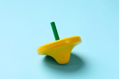 Photo of One yellow spinning top on light blue background, closeup