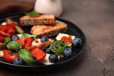 Delicious salad with brie cheese, berries and balsamic vinegar on brown table, closeup