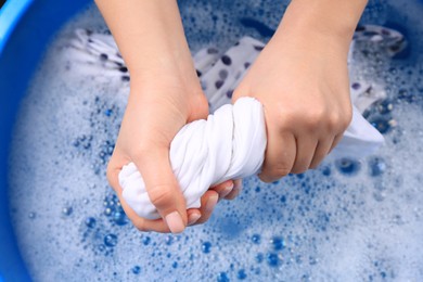 Photo of Woman wringing garment over basin, closeup. Hand washing laundry