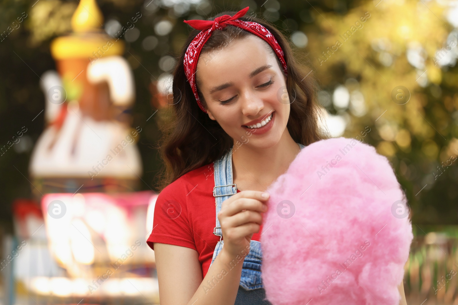 Photo of Stylish young woman with cotton candy at funfair