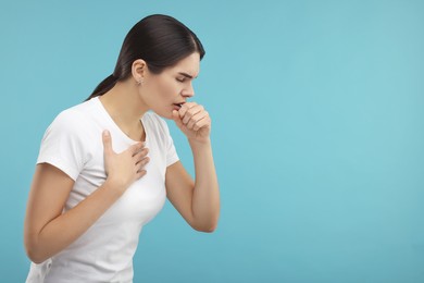 Photo of Woman coughing on light blue background, space for text. Cold symptoms