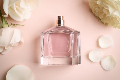Photo of Bottle of perfume, beautiful flowers and petals on beige background, flat lay
