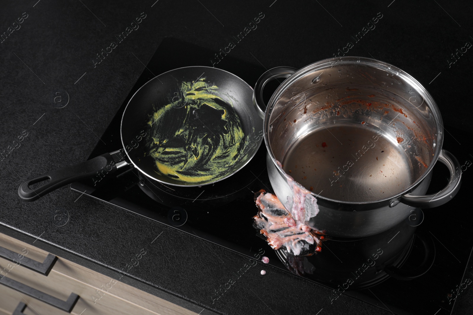 Photo of Dirty pot and frying pan on cooktop in kitchen, above view