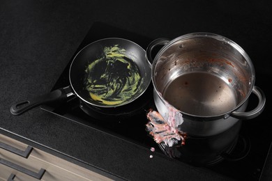 Photo of Dirty pot and frying pan on cooktop in kitchen, above view