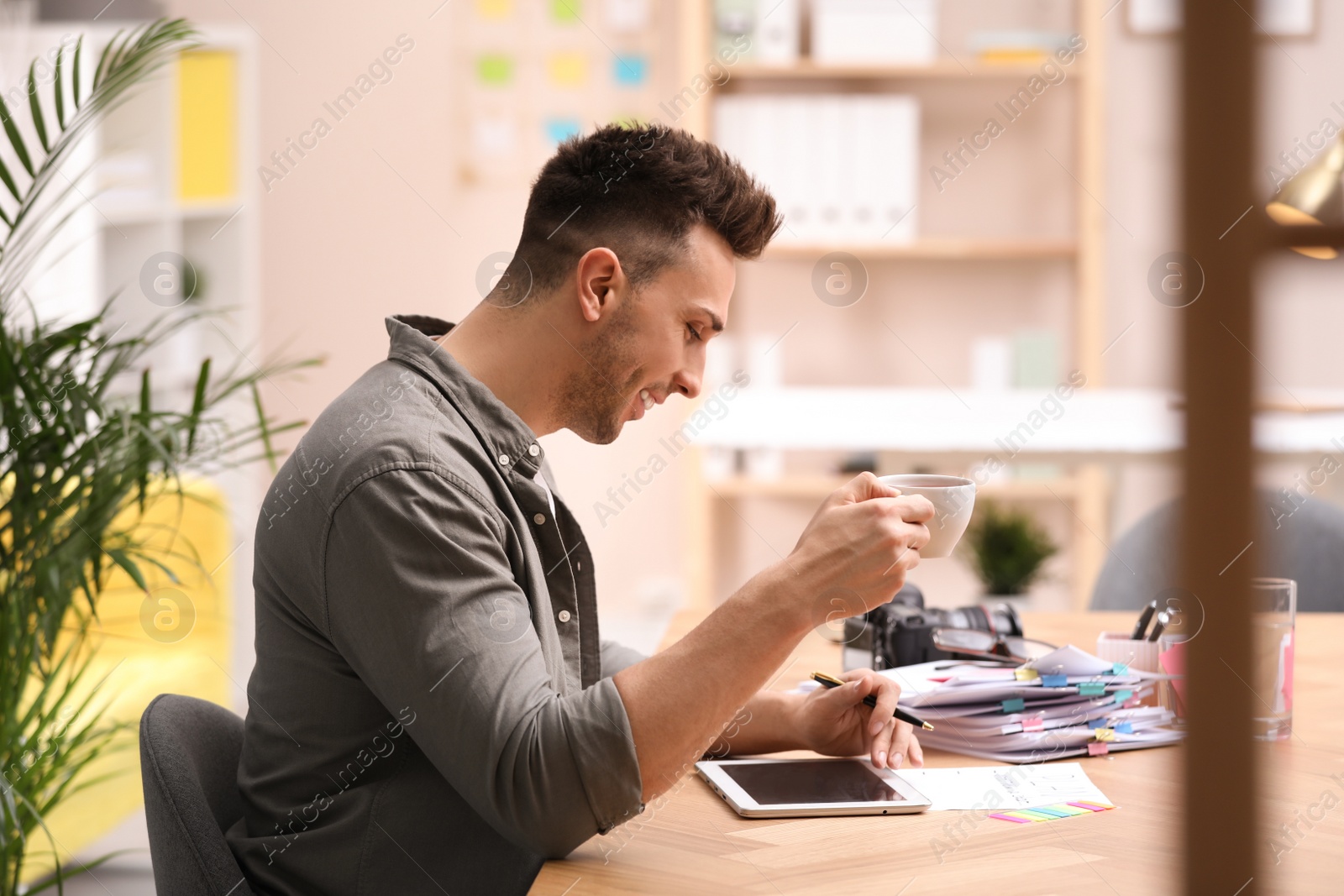 Photo of Journalist with tablet and coffee at workplace in office