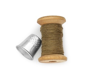 Thimble and spool of brown sewing thread isolated on white, top view