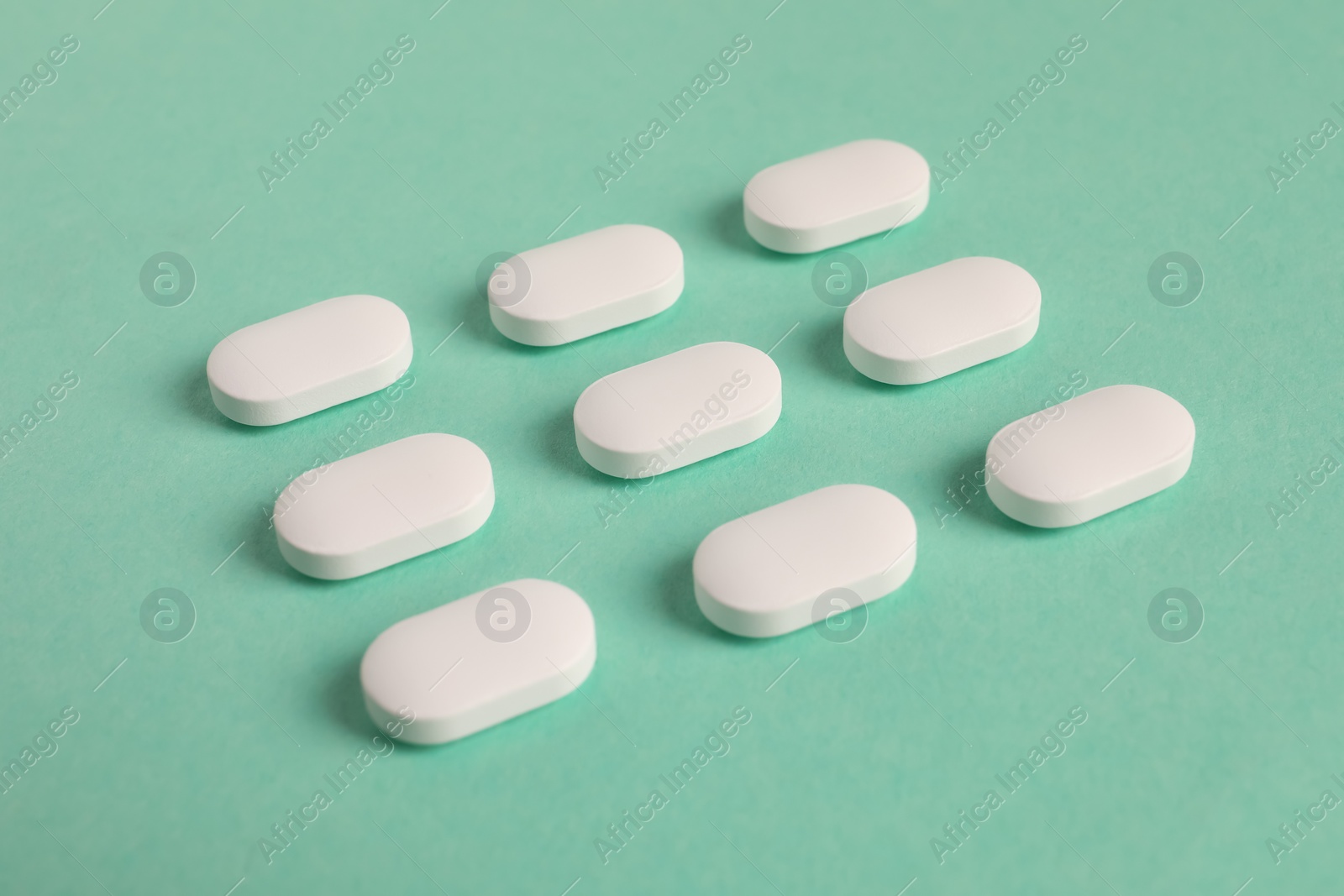 Photo of Many white pills on green background. Medicinal treatment