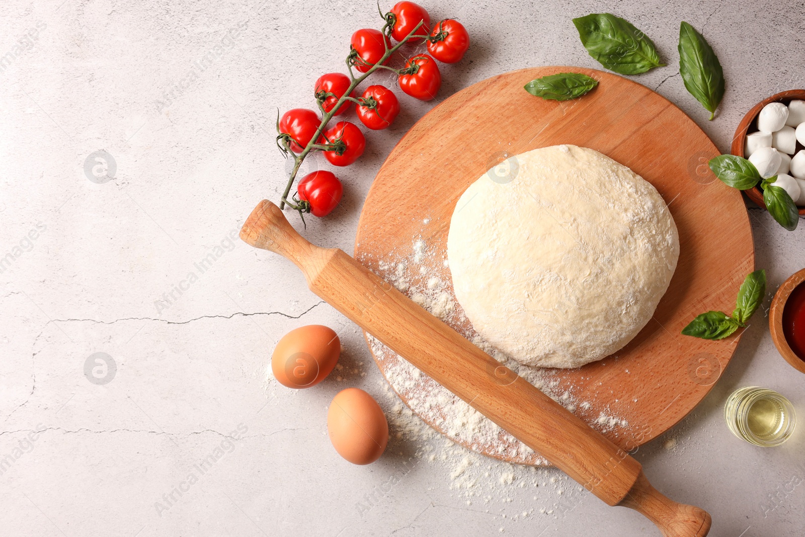 Photo of Pizza dough, products and rolling pin on gray textured table, flat lay. Space for text