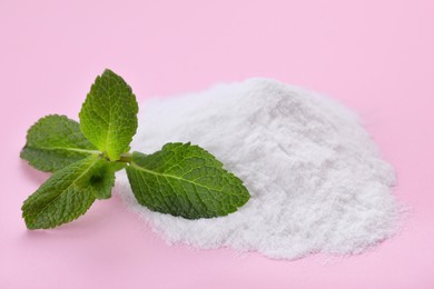 Photo of Sweet powdered fructose and mint leaves on pink background