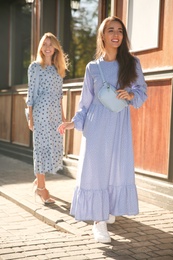 Photo of Beautiful young women in stylish blue dresses on city street