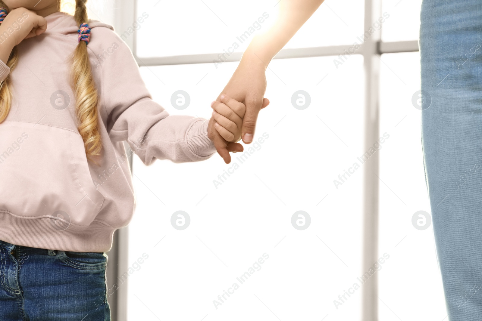 Photo of Mother holding hands with her child indoors, closeup. Happy family