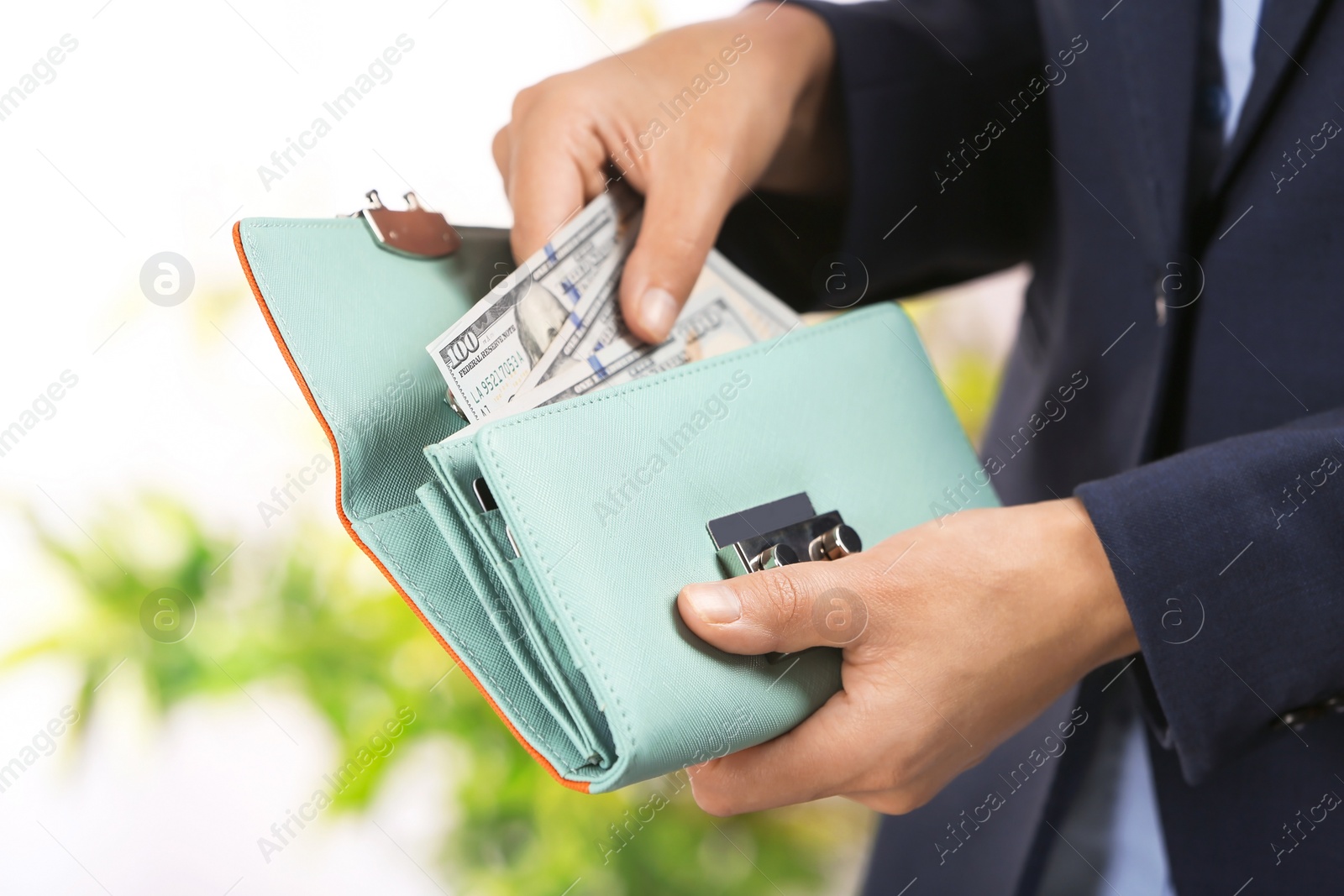 Photo of Woman taking out cash from stylish wallet on blurred background, closeup