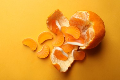 Photo of Delicious gummy candies and fresh fruit on orange background