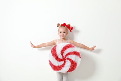 Cute little girl dressed as candy on white background. Christmas suit