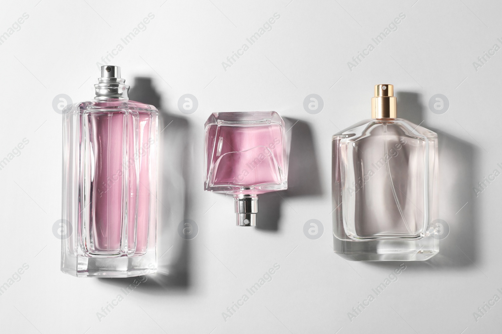 Photo of Bottles of perfume on light background, top view