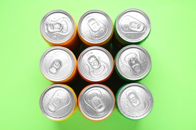 Energy drinks in wet cans on green background, top view