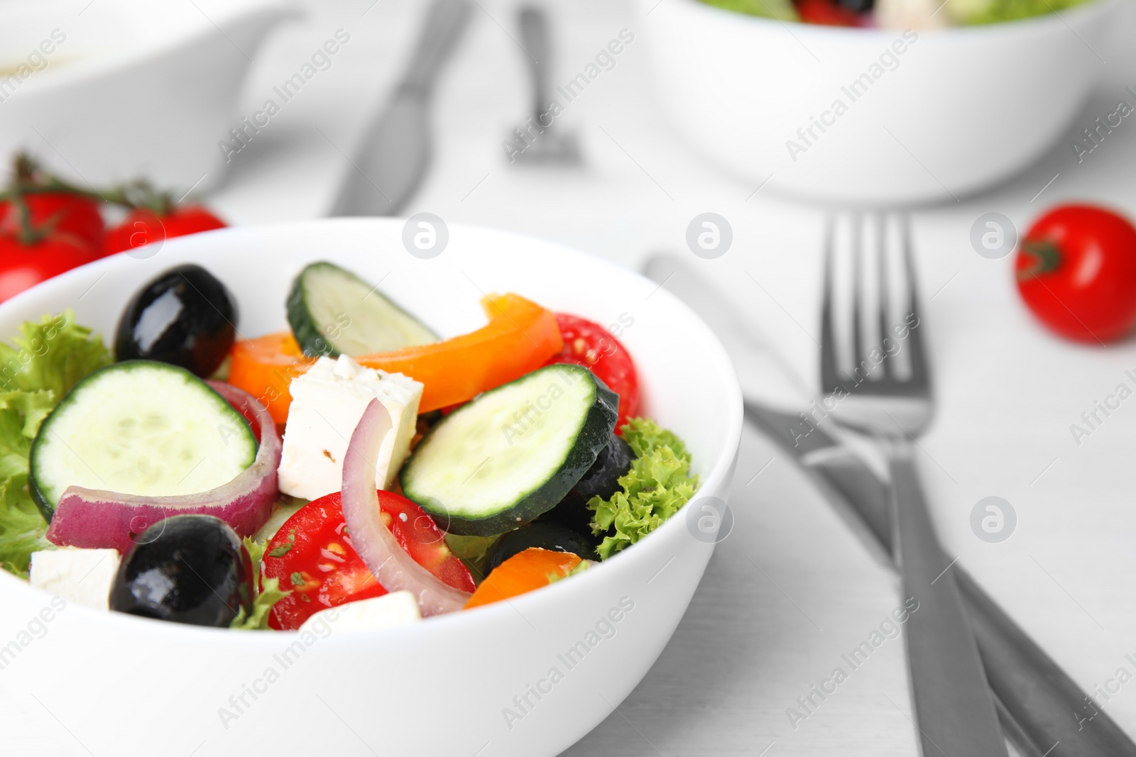 Photo of Tasty fresh Greek salad on white wooden table, closeup