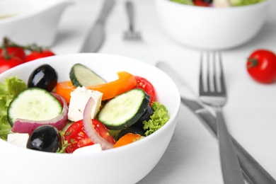 Tasty fresh Greek salad on white wooden table, closeup