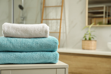 Stack of clean towels on table indoors. Space for text