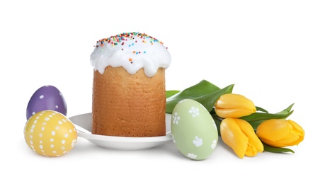 Photo of Traditional Easter cake, tulips and colorful eggs on white background