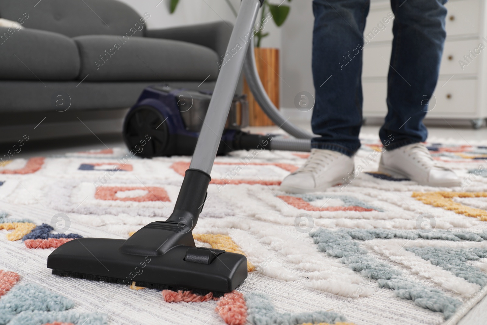Photo of Man cleaning carpet with vacuum cleaner at home, closeup. Space for text