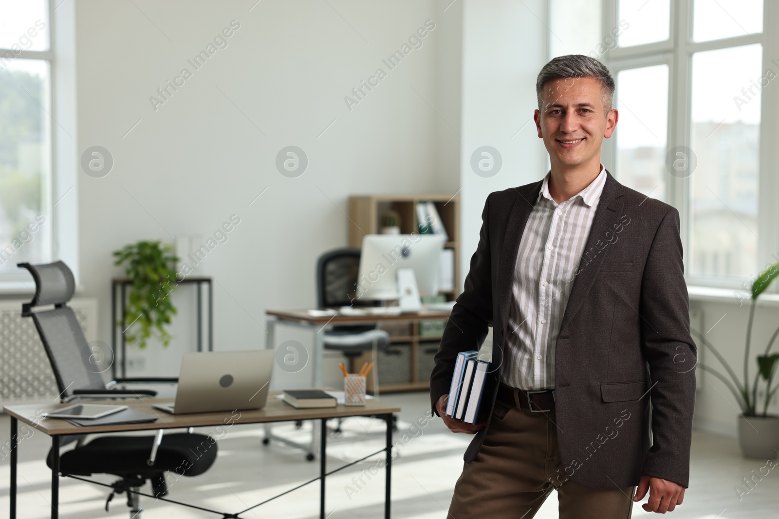 Photo of Portrait of happy man with notebooks in office