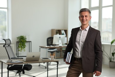 Portrait of happy man with notebooks in office