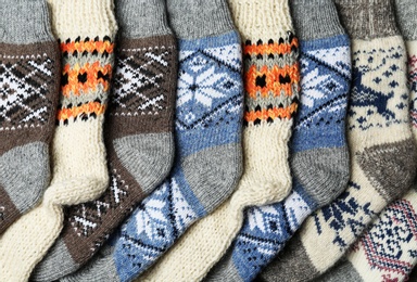 Photo of Different knitted woolen socks as background, top view