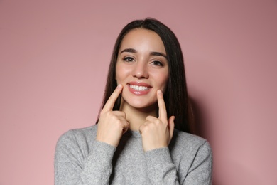 Woman showing LAUGH gesture in sign language on color background