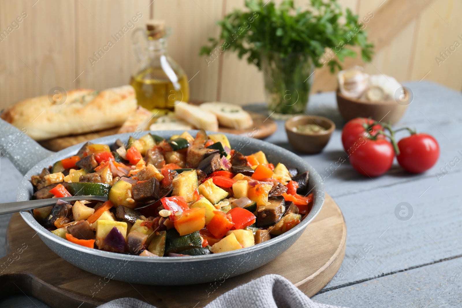Photo of Delicious ratatouille in frying pan on grey wooden table, closeup. Space for text