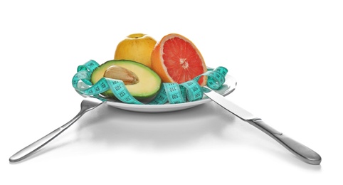 Plate with different tasty fruits and measuring tape on white background. Healthy diet