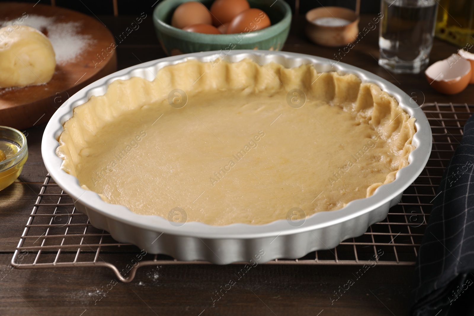 Photo of Pie tin with fresh dough and ingredients on wooden table. Making quiche