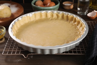 Pie tin with fresh dough and ingredients on wooden table. Making quiche