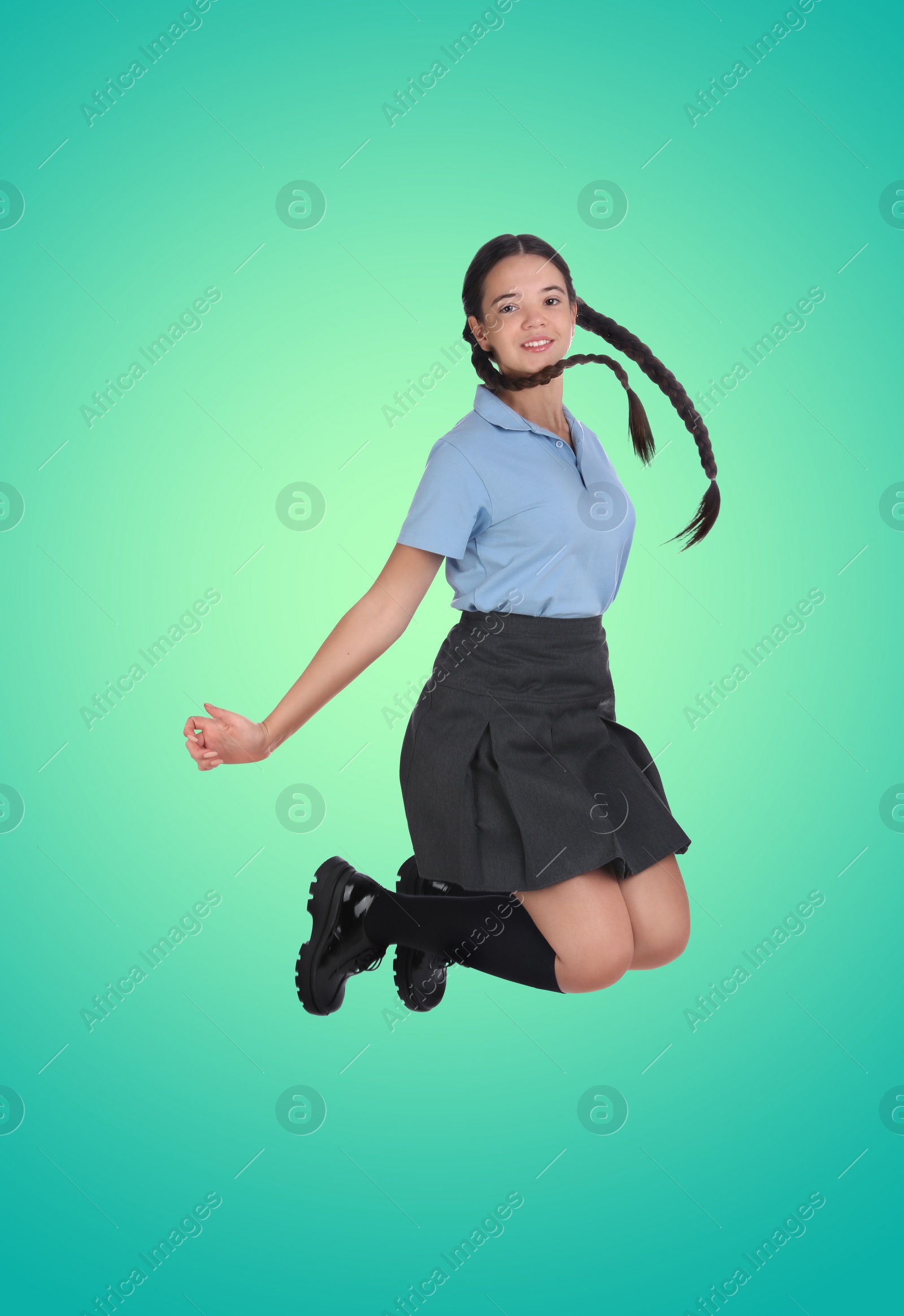 Image of Happy cute girl in school uniform jumping on color gradient background