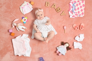 Photo of Cute little baby with clothing and accessories on color blanket, top view