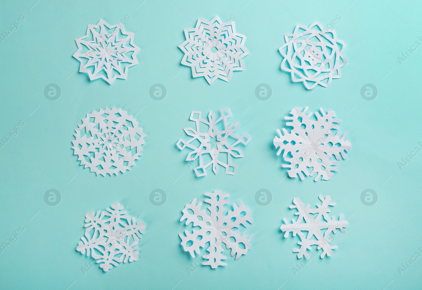 Photo of Flat lay composition with paper snowflakes on cyan background