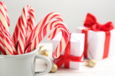 Photo of Many sweet candy canes in cup on table, closeup. Traditional Christmas treat