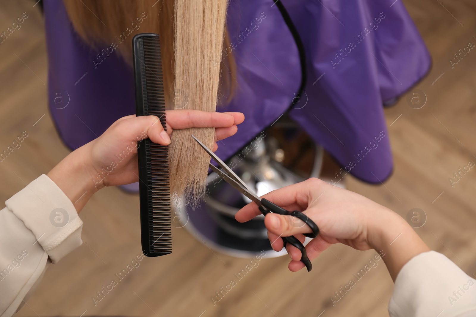 Photo of Stylist cutting hair of client in professional salon, closeup