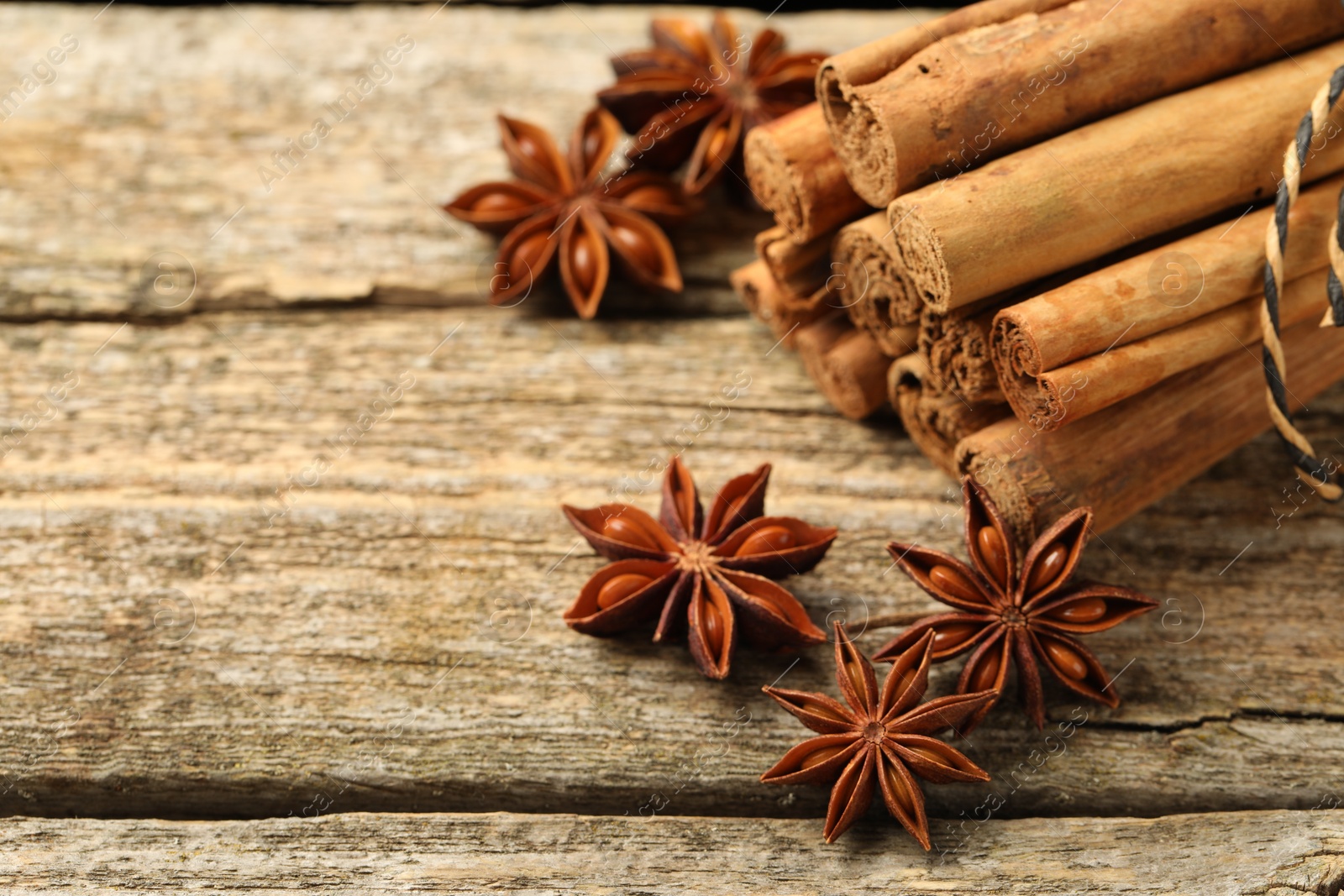 Photo of Cinnamon sticks and star anise on wooden table, closeup. Space for text