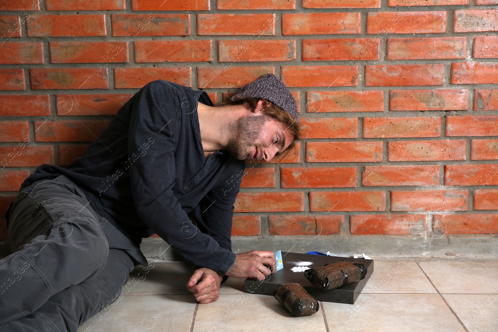 Photo of Young addicted man taking drugs near brick wall. Space for text