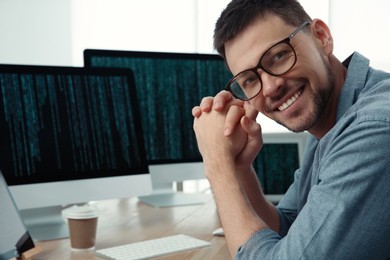 Happy programmer working at desk in office