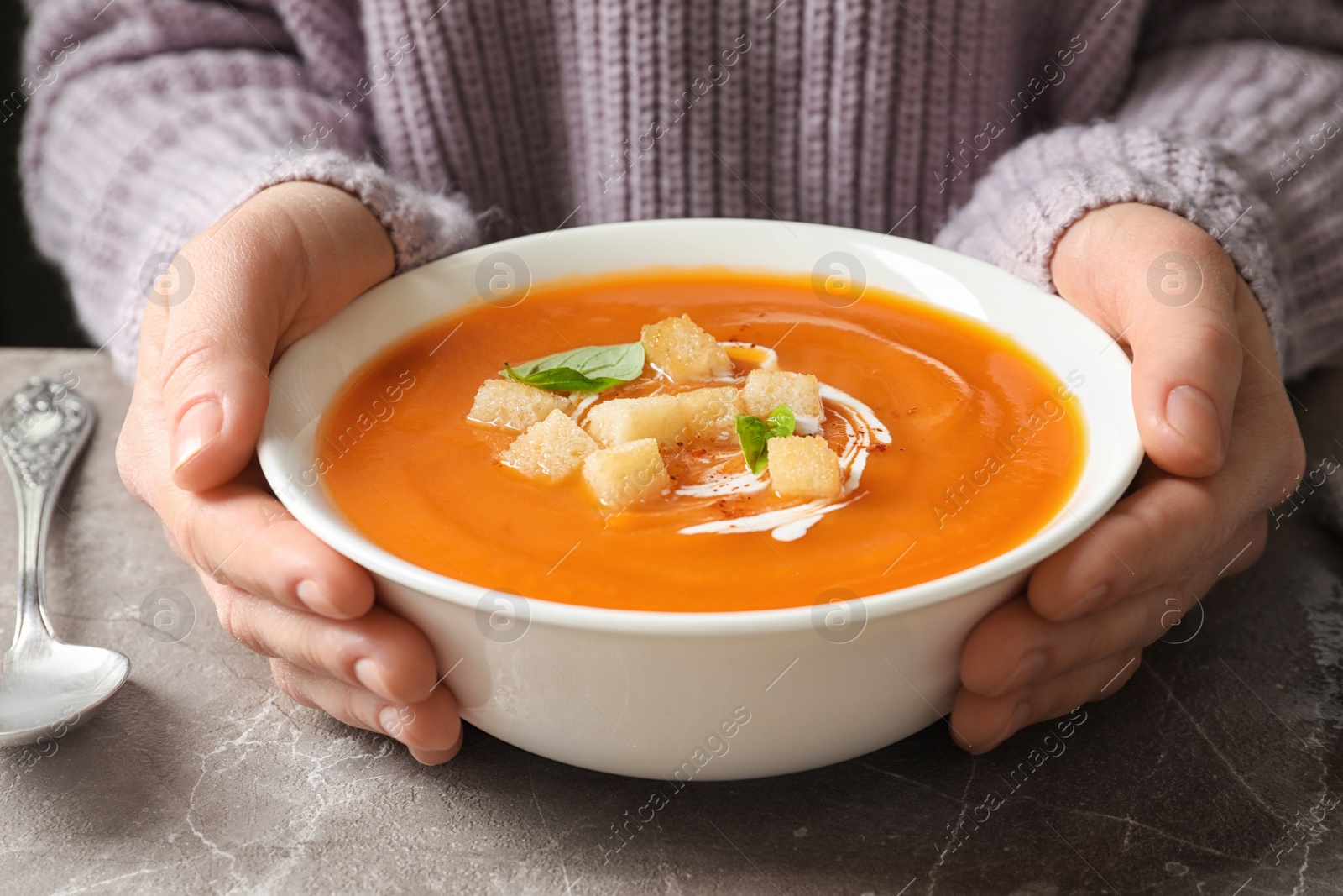 Photo of Woman with bowl of tasty sweet potato soup at table, closeup
