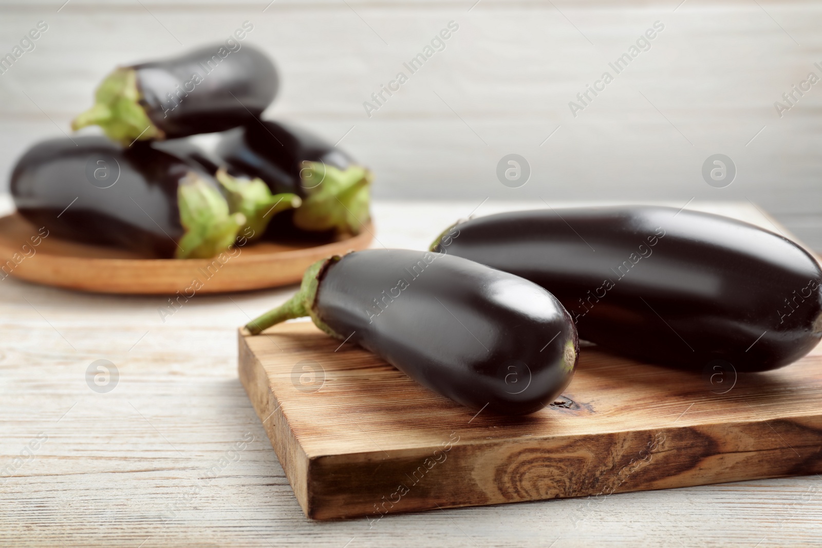 Wooden board with ripe eggplants on table Photo of Wooden board with ripe eggplants on table