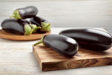 Photo of Wooden board with ripe eggplants on table